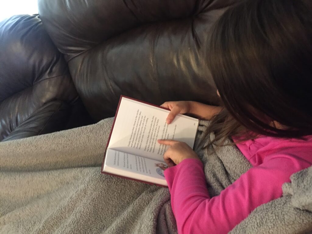 child reading a book cozied up on the couch
